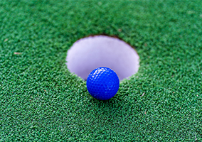 blue golf ball on rim of hole