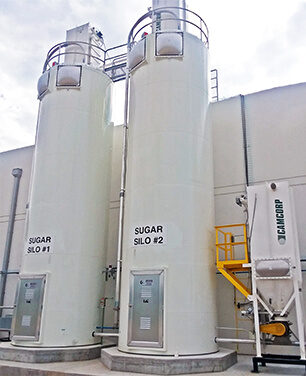 Two adjacent, sizeable white silos positioned in close proximity to each other.