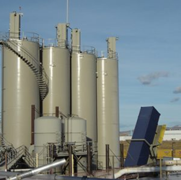 Four adjacent, sizeable tan silos positioned in close proximity to each other
